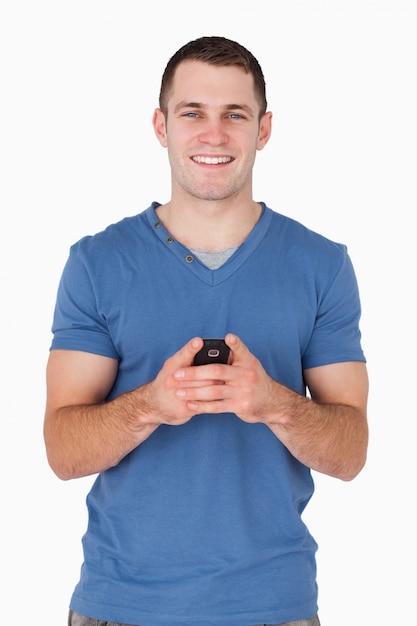 Portret van een glimlachende mens die zijn mobiele telefoon houdt