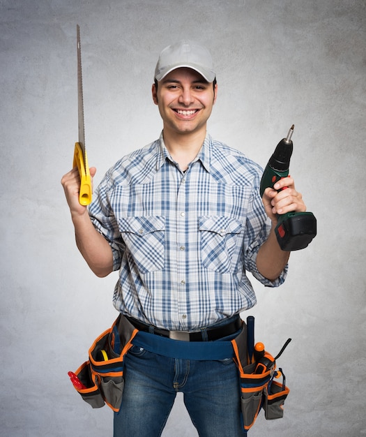 Foto portret van een glimlachende timmerman die houten planken houdt. grijze grungeachtergrond