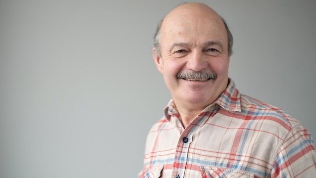 Portret van een glimlachende volwassen man die op een grijze achtergrond staat