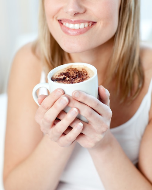 Portret van een glimlachende vrouw die een koffie drinkt