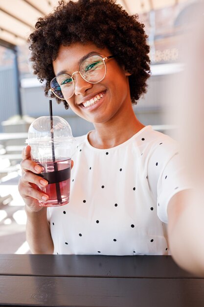 Foto portret van een glimlachende vrouw die in een café drinkt