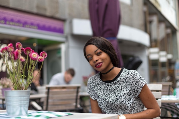 Portret van een glimlachende vrouw die op een stoep café zit