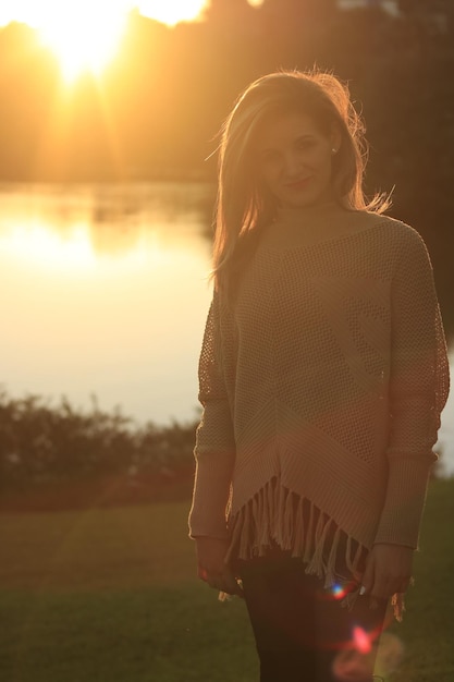 Foto portret van een glimlachende vrouw die op het veld tegen het meer staat