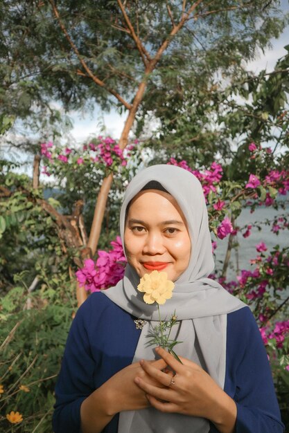 Foto portret van een glimlachende vrouw met een bloeiende plant
