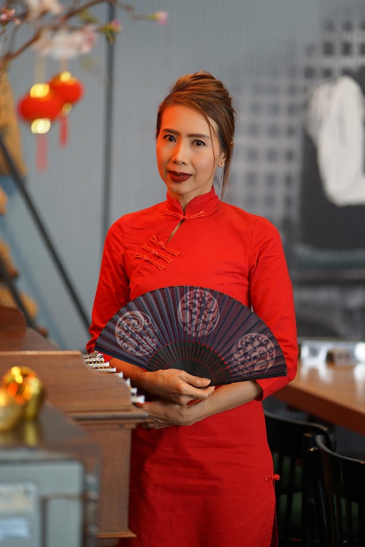 Foto portret van een glimlachende vrouw met een handventilator terwijl ze bij de tafel staat
