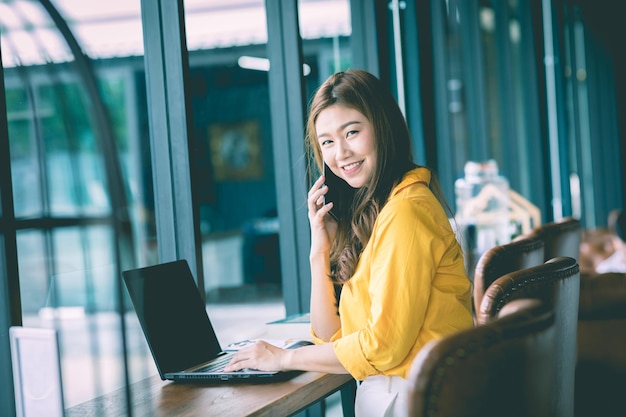Portret van een glimlachende vrouw met een laptop in een café