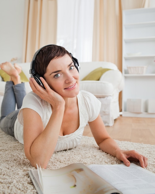 Portret van een glimlachende vrouw met een tijdschrift dat van wat muziek geniet