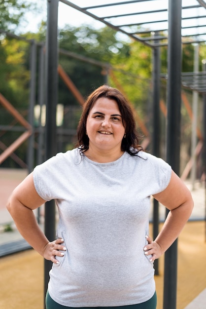 Portret van een glimlachende vrouw met overgewicht in een tracksuit op een sportveld in een park