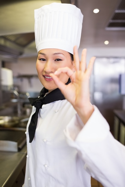 Portret van een glimlachende vrouwelijke kok die ok teken gesturing