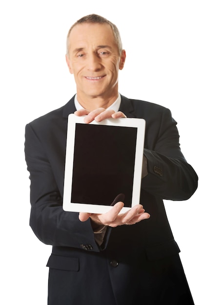 Portret van een glimlachende zakenman die een digitale tafel vasthoudt terwijl hij tegen een witte achtergrond staat