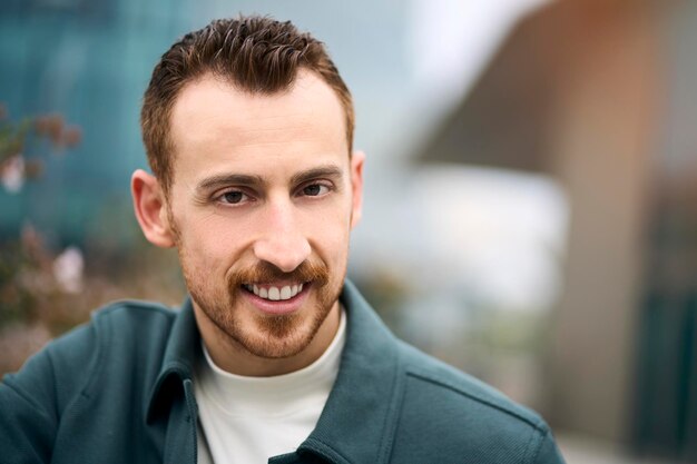 Portret van een glimlachende zelfverzekerde man die zich voordeed op de camera in het zakendistrict