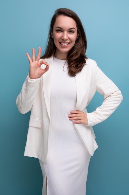 Portret van een goed verzorgde zelfverzekerde jonge brunette zakenvrouw in een witte jurk en jas