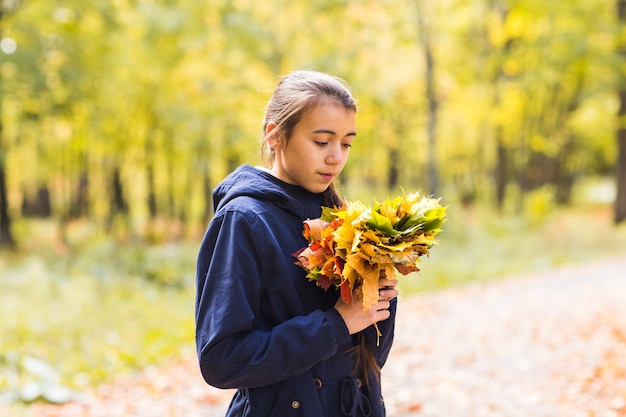 Portret van een grappig jong meisje in het de herfstweer in warme kleren en hoed