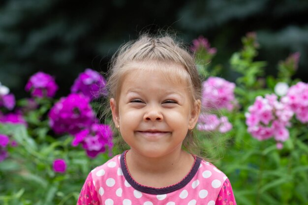 Portret van een grappig kaukasisch meisje met loensende ogen van vier jaar oud die naar de camera kijkt in het zomerpark