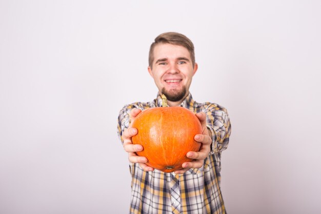 Portret van een grappige boer die pompoenen vasthoudt op een lichte studio als achtergrond