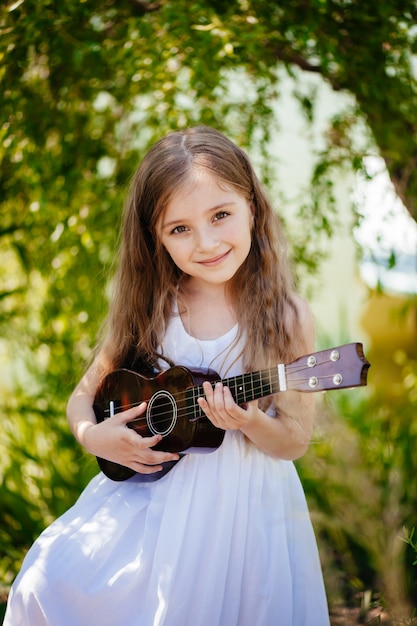 Portret van een grappige jonge vrouw die ukelele speelt