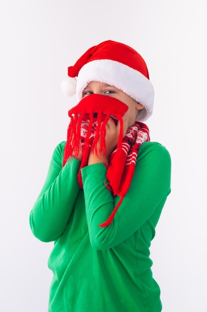 Foto portret van een grappige jongen met een kerstmuts en een wintersjaal kind dat plezier heeft met kerstmis