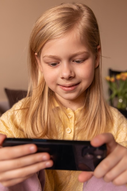 Portret van een grappige, schattige meisjesglimlach naar de telefoon