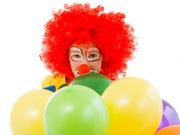 Foto portret van een grappige speelse clown in rode pruik met ballonnen.