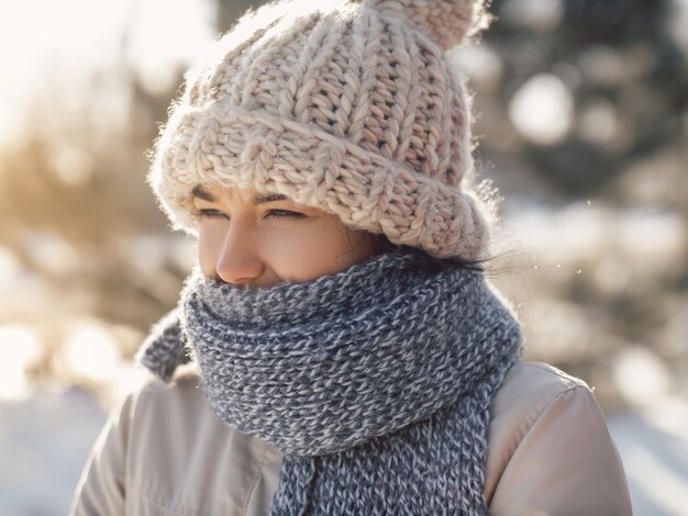 Portret van een grappige vrouw in casual winterkleren, muts, sjaal en jas die lijden aan een verkoudheid