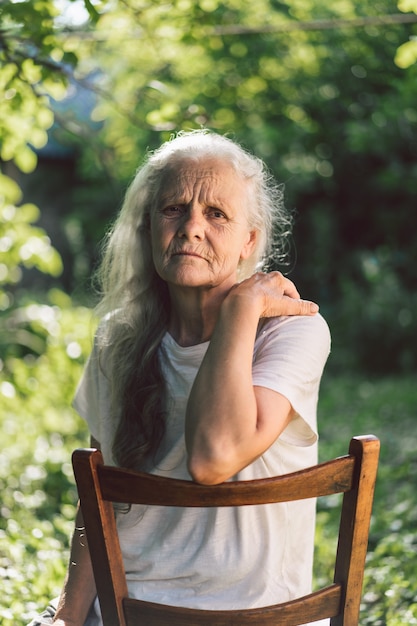 Portret van een grijsharige volwassen grootmoeder tegen de achtergrond van de natuur