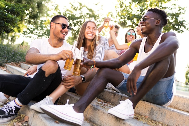 Portret van een groep jongeren die roosteren met bier in een stedelijk gebied.