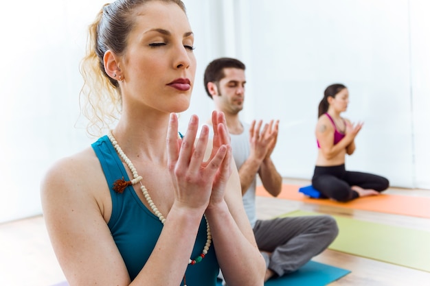 Portret van een groep mensen die thuis yoga beoefenen in de lotuspositie.