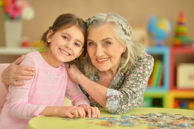 Portret van een grootmoeder die puzzel verzamelt met haar kleindochter