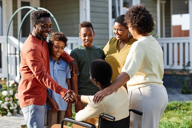 Portret van een grote afro-amerikaanse familie met een persoon in een rolstoel die buiten aan het chatten is tijdens het verzamelen