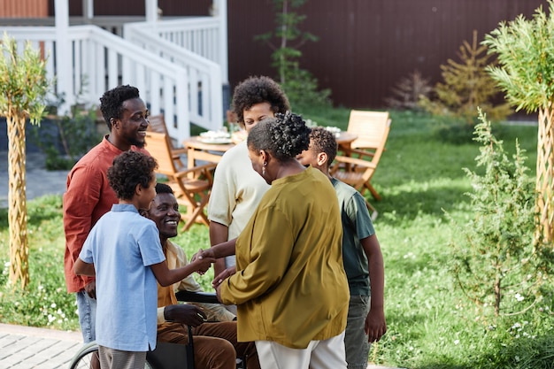 Portret van een grote Afro-Amerikaanse familie met een persoon in een rolstoel die in de zomer buiten aan het chatten is