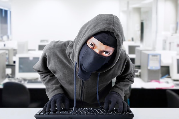Portret van een hacker met een toetsenbord aan zijn bureau in het kantoor