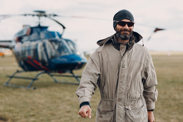 Portret van een helikopterpiloot die in de buurt van het voertuig op de veldluchthaven staat.