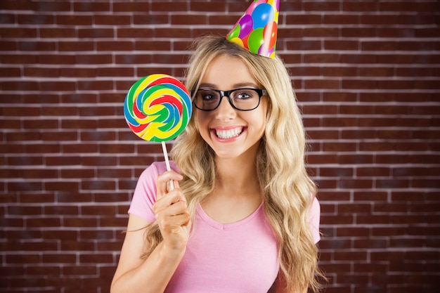 Portret van een hipster met een feestmuts die een lolly houdt