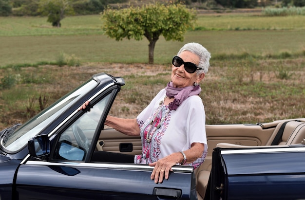 Portret van een hogere vrouw met convertibele auto