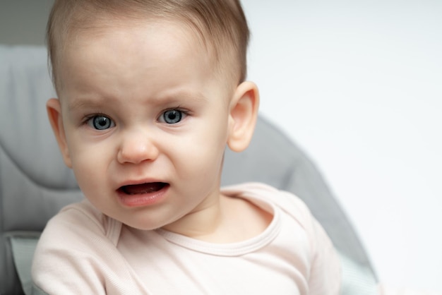 Foto portret van een huilende eenjarige baby die overstuur is over honger en vermoeidheid