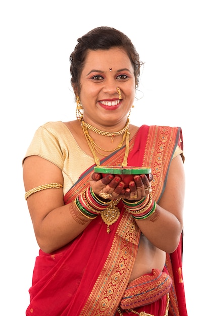 Foto portret van een indisch traditioneel meisje dat pooja thali met diya houdt tijdens festival van licht op wit