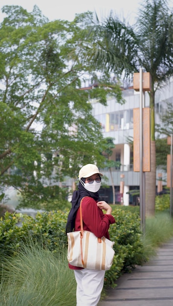 portret van een Indonesische moslimvrouw die een rood-witte jurk draagt en een tas draagt met een ma