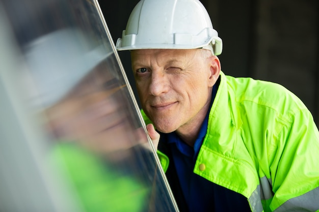 Foto portret van een ingenieur die op zonnecelpaneel kijkt