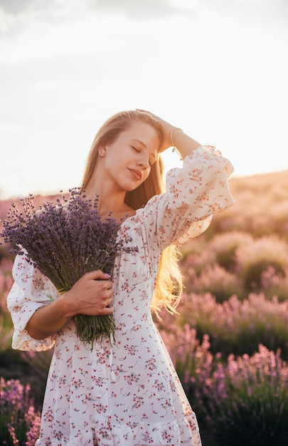 Portret van een jong blond meisje in een lavendelveld in de zomer bij zonsondergang