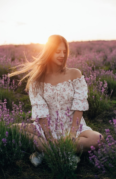 Portret van een jong blond meisje in een lavendelveld in de zomer bij zonsondergang