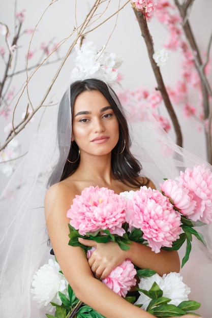 Portret van een jong heet model dat een bos bloemen omhelst en naar de camera kijkt Foto van hoge kwaliteit