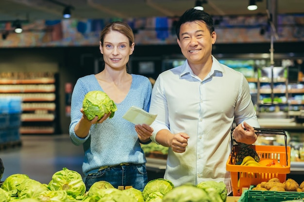 Portret van een jong interraciaal stel, een europese vrouw en een aziatische man kopen groenten groen