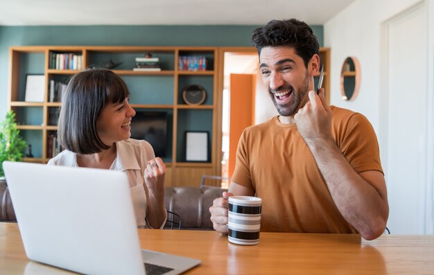 Portret van een jong koppel online winkelen met een creditcard en een laptop vanuit huis. E-commerce concept