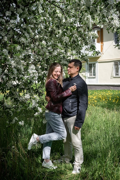 Portret van een jong koppel verliefde man en vrouw in een lente bloeiend park knuffelen en lachen familie goede relatie concept