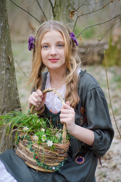 Portret van een jong meisje dat een mand met wilde bloemen vasthoudt en wegkijkt