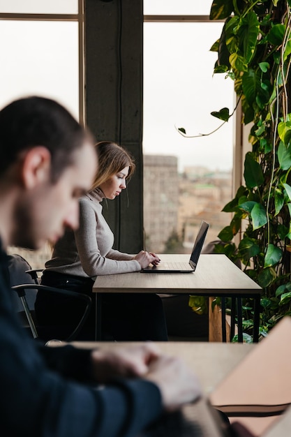 Portret van een jong meisje dat op een laptop werkt en in een moderne coworking-ruimte zit