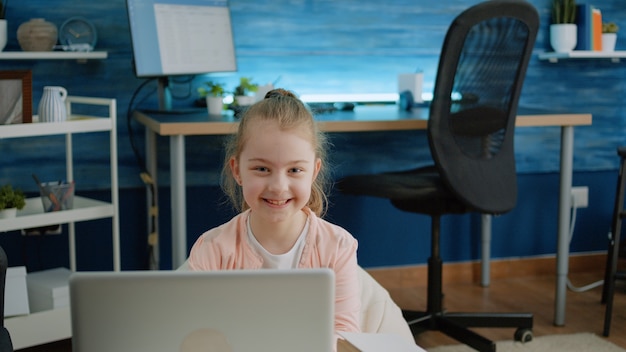 Portret van een jong meisje glimlachend en met laptop thuis