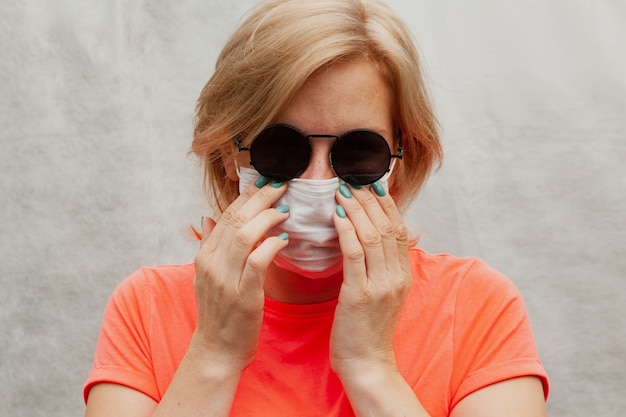 Portret van een jong meisje in een medisch masker op haar gezicht met ronde bril.