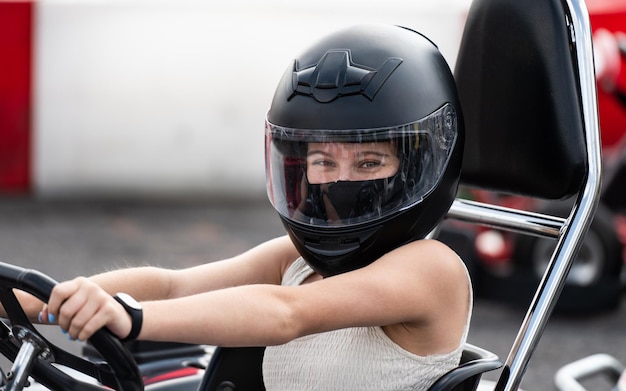 Portret van een jong meisje met een beschermende helm in een gokart op een spoor