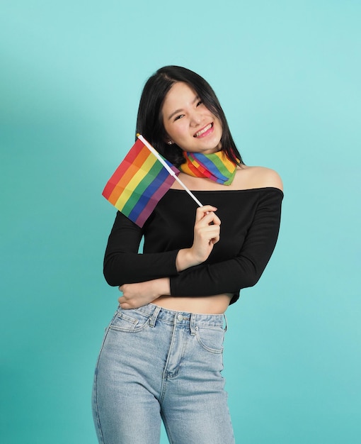 Portret van een jong meisje met een LGBT-vlag staande tegen een blauwgroene studio als achtergrond